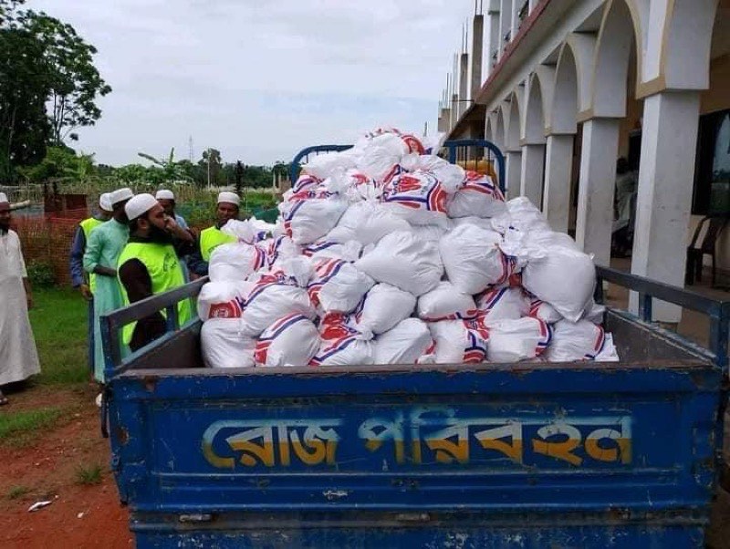 Truck loaded with sacks of food aid while volunteers in hi-vis vests look on